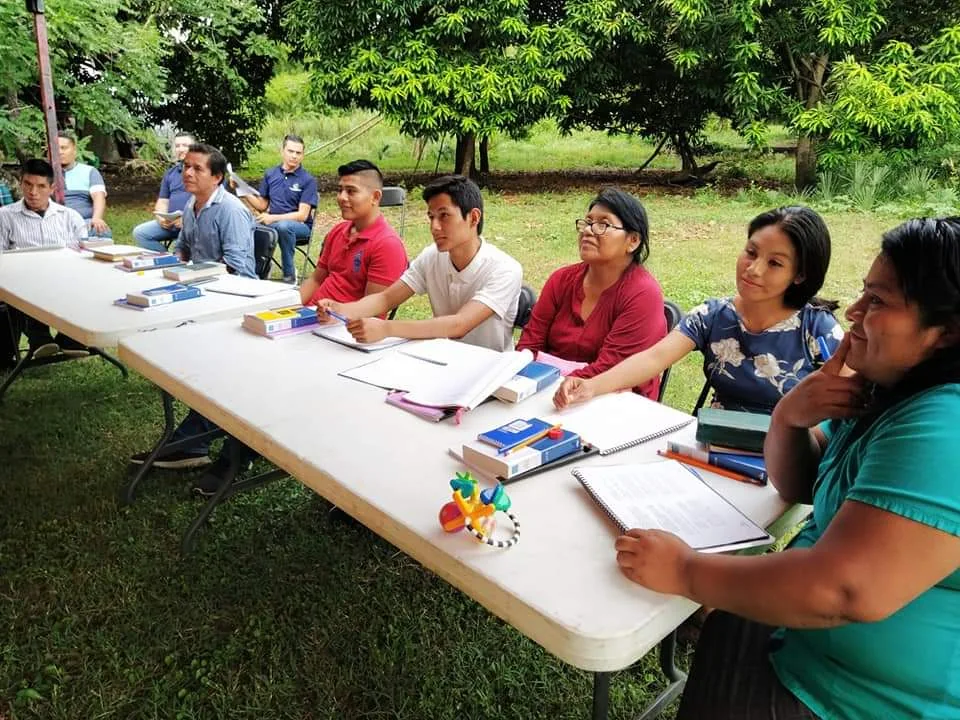 Estudiantes reunidos alrededor de una mesa con materiales de estudio