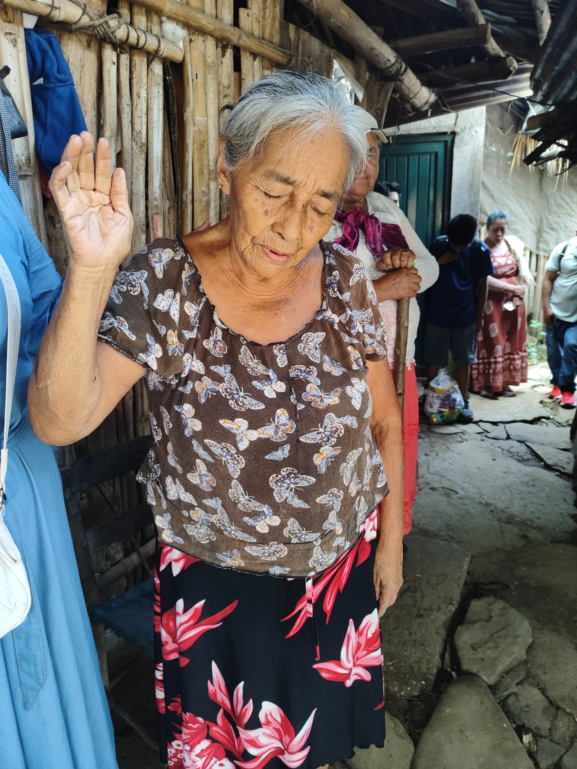 Una mujer saluda desde la entrada de su casa